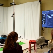 Model student stands in front of white screens of Motion Capture Studio