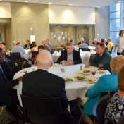 Chemistry faculty and staff seated around a table with the Otienos.