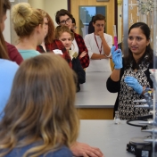 Dr. Radhika Dasari shows students a test tube with pink liquid.