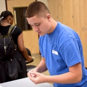 Male student adds beads to a pipe cleaner in the water game