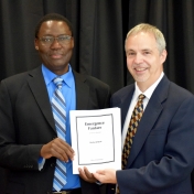 Tom Otieno and Richard Byrd pose with sheet music for commissioned musical piece