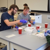 Model students smash strawberries for a lab experiment